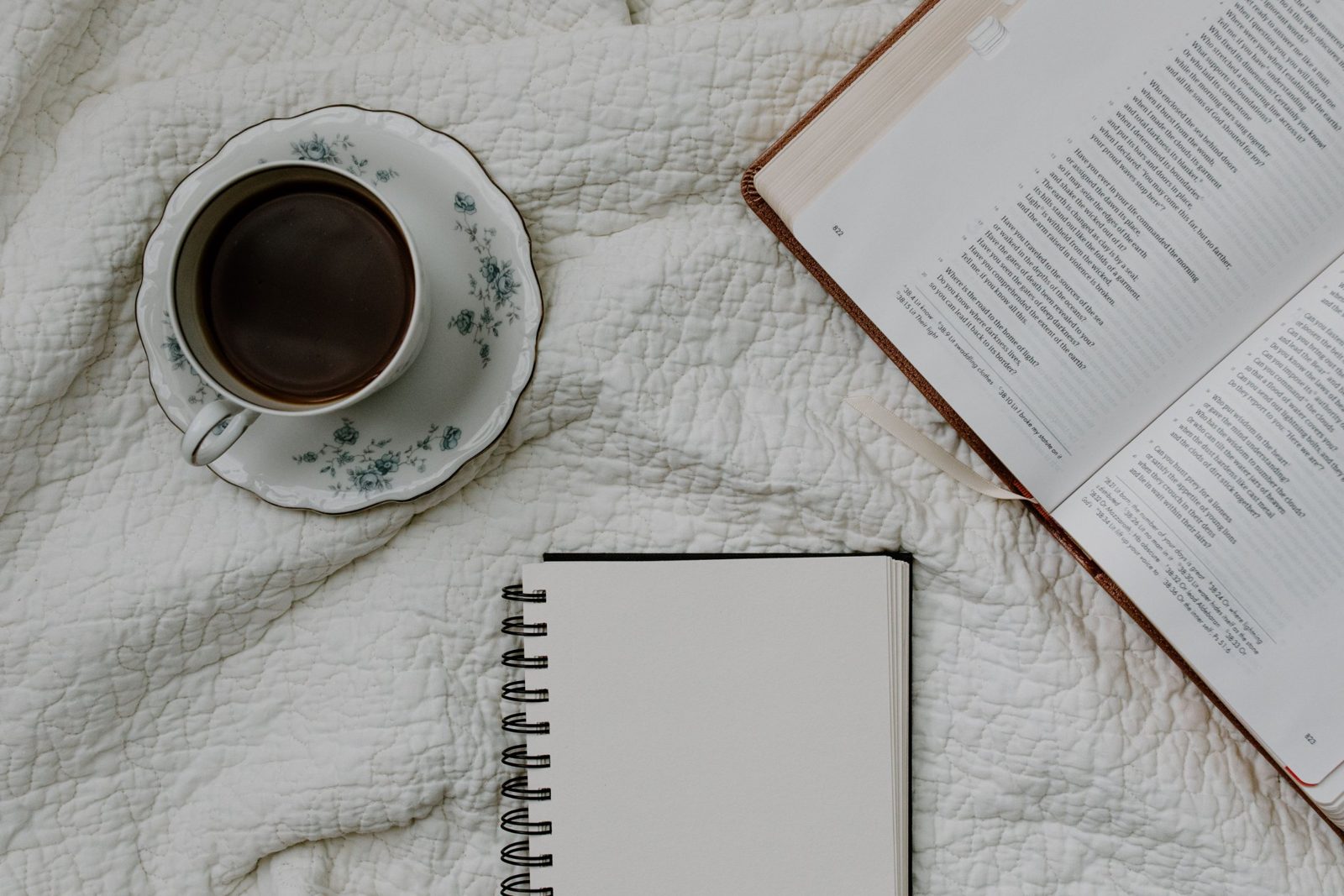 An open Bible, a blank journal, and a cup of coffee
