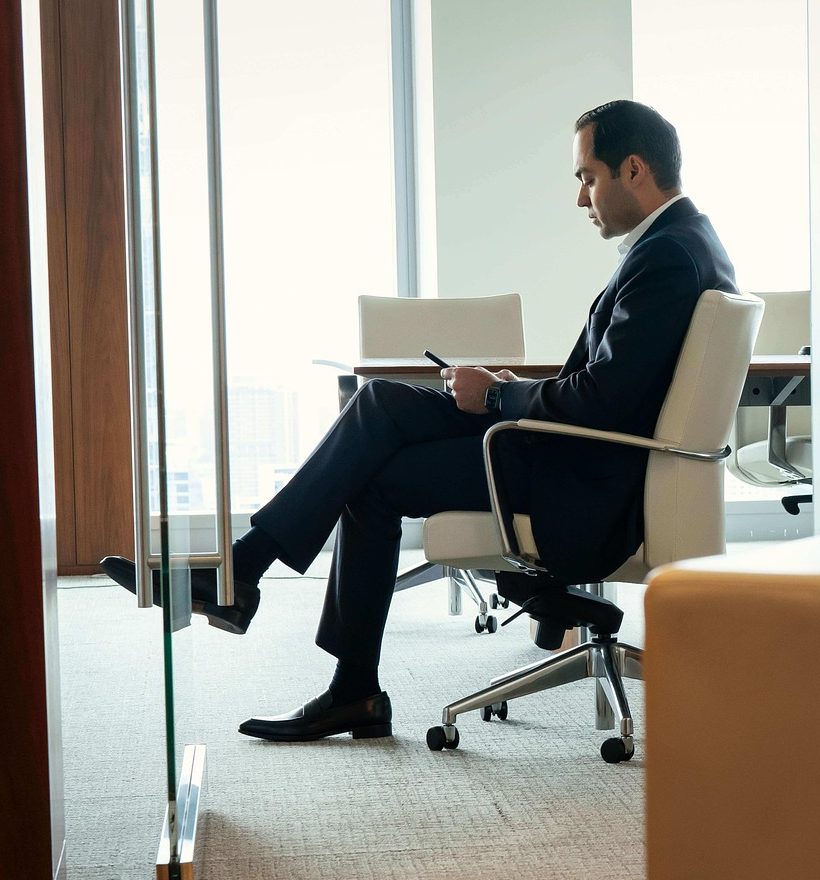A businessman sitting alone in an empty boardroom