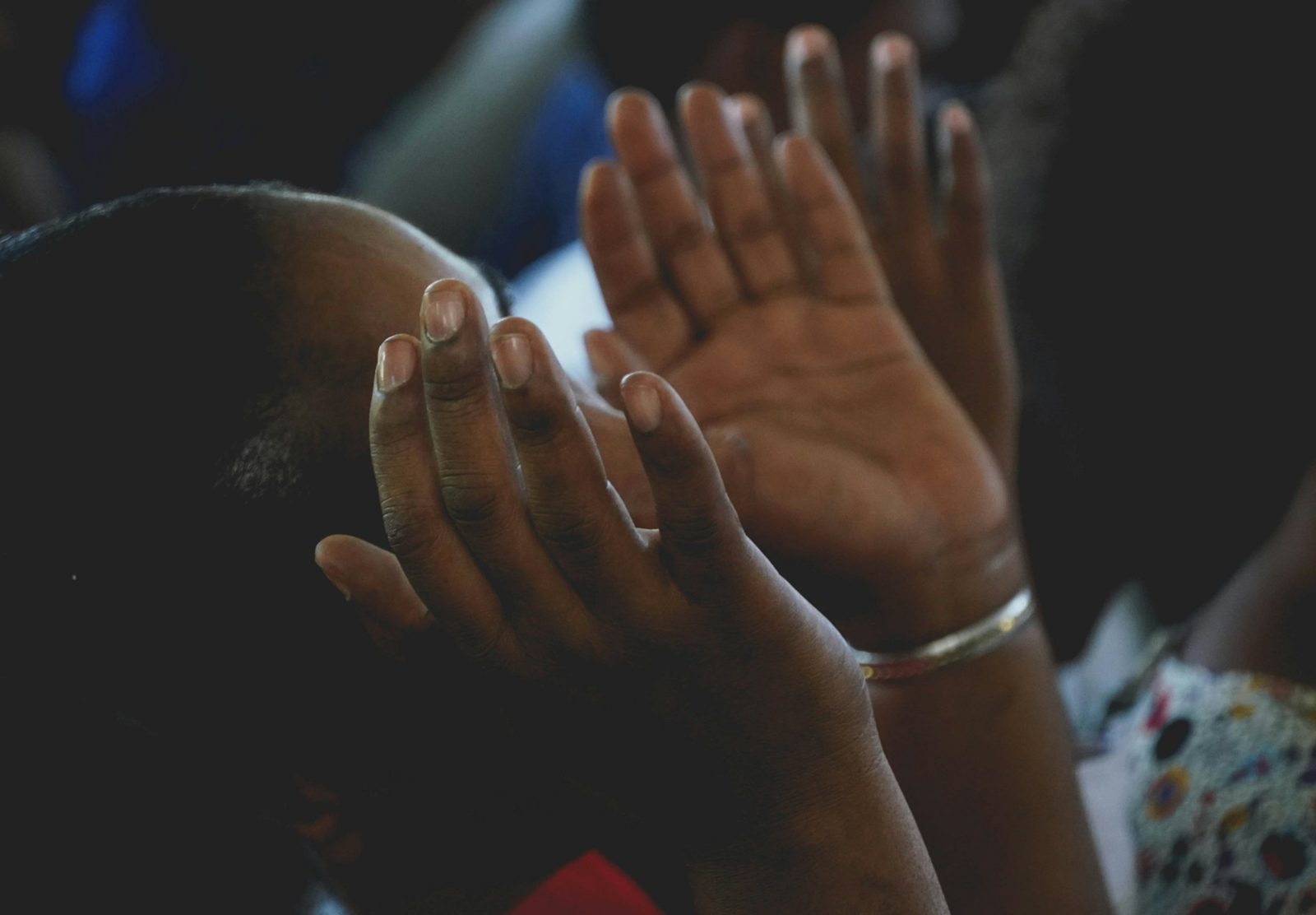 Hands lifted in prayer with head bowed